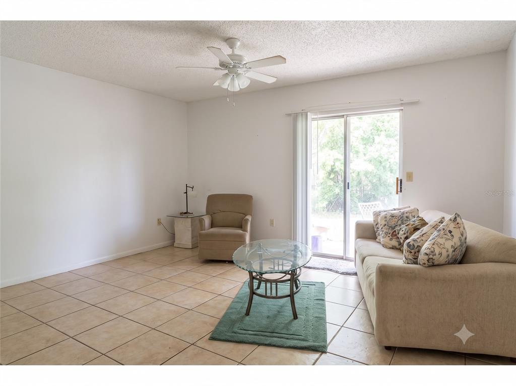 A living room features tile flooring, a ceiling fan, a sofa, and a sliding glass door — 4975 DAVID AVENUE, SARASOTA, FL