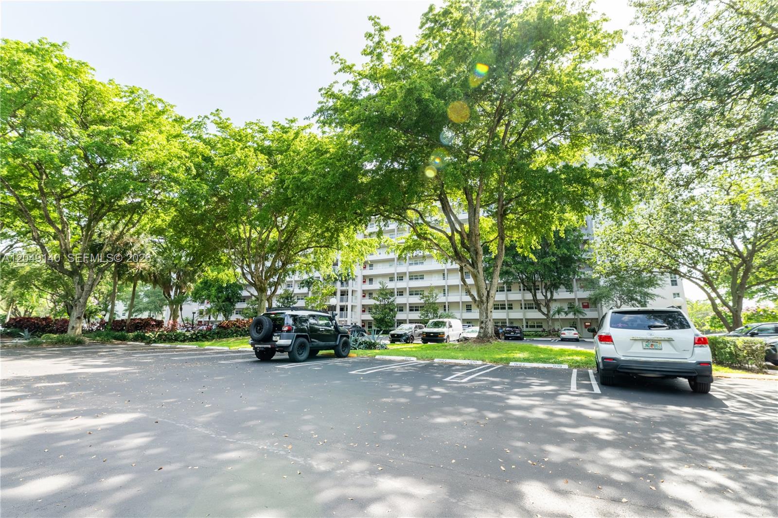 A parking lot with several cars sits in front of a multi-story apartment building — 605 Oaks Dr # 607, Pompano Beach FL 33069, POMPANO BEACH, FL