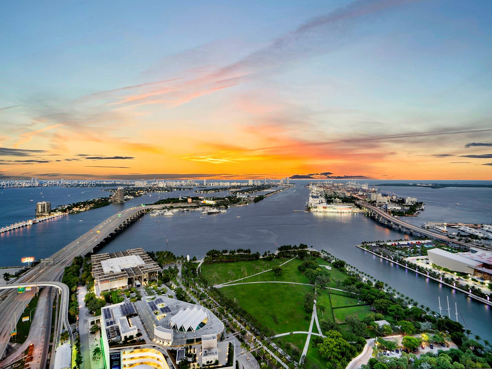 An aerial view shows a park, a bridge, and a port at sunset in Miami — 1100 Biscayne Blvd # 4001, Miami FL 33132, MIAMI, FL