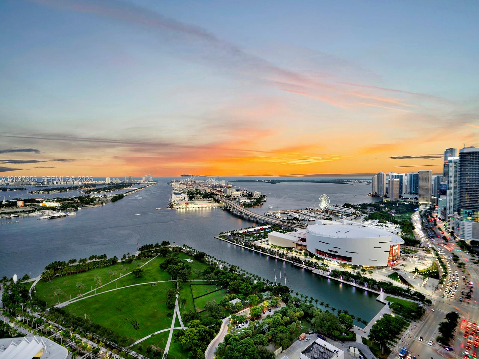 An aerial view of a city waterfront, park, arena, and bridge at sunset — 1100 Biscayne Blvd # 4001, Miami FL 33132, MIAMI, FL