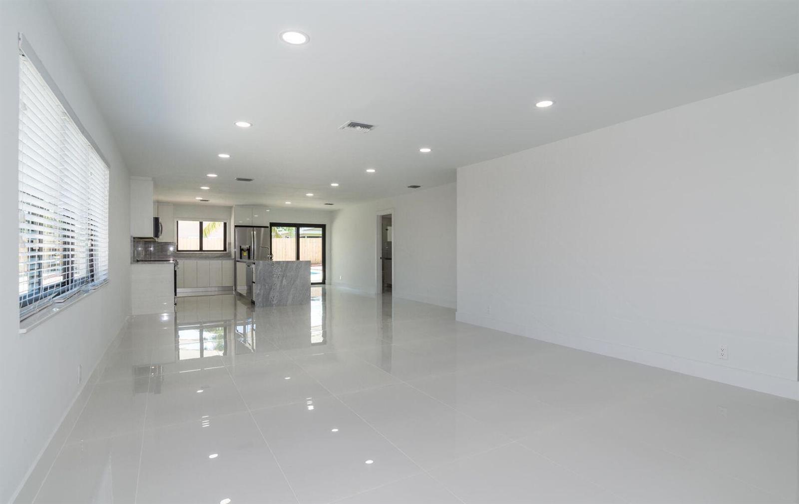 An open-concept living area with white walls, glossy tile flooring, and a modern kitchen — 524 NW 53rd Street, Boca Raton FL 33487, BOCA RATON, FL