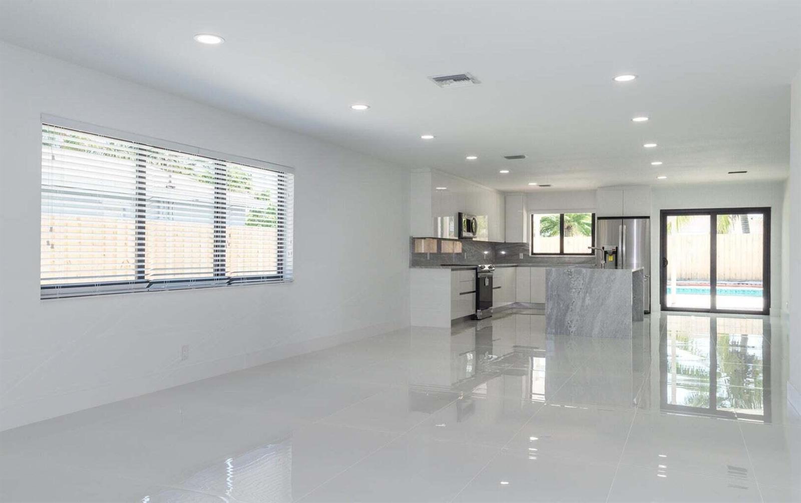 A bright, open-concept kitchen and living area featuring white walls, glossy tile floors, and cabinetry — 524 NW 53rd Street, Boca Raton FL 33487, BOCA RATON, FL