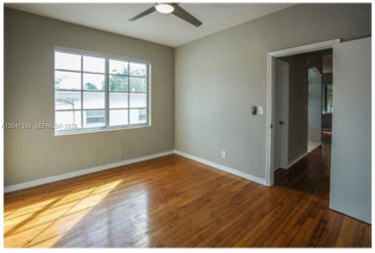 An empty bedroom features hardwood floors, light gray walls, a ceiling fan, and a window — 715 Michigan Ave # 7, Miami Beach FL 33139, MIAMI BEACH, FL
