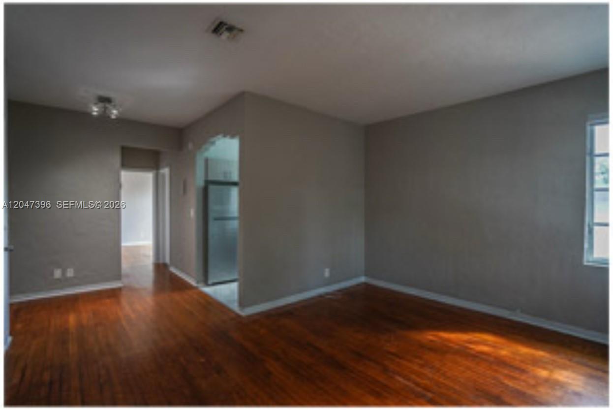 An interior room features hardwood flooring, gray walls, and an arched entryway to the kitchen — 715 Michigan Ave # 7, Miami Beach FL 33139, MIAMI BEACH, FL