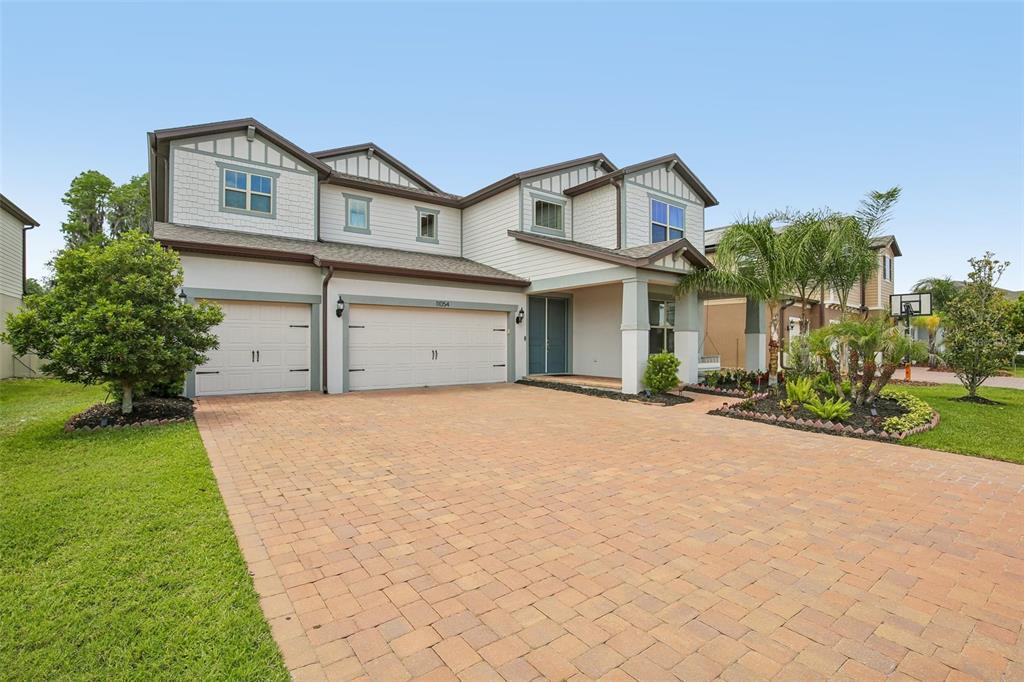 A two-story house with a brick paver driveway, three-car garage, and a covered front porch — 11054 SUNDRIFT DRIVE, TAMPA, FL