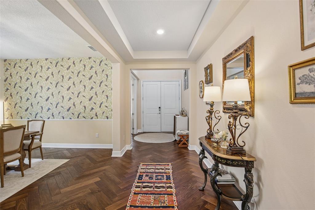 A foyer with herringbone wood floors leads to a white double-door entrance and dining area — 11054 SUNDRIFT DRIVE, TAMPA, FL