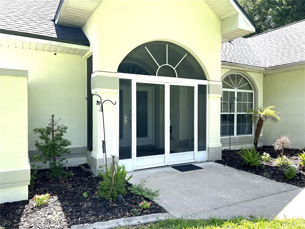 The exterior of a house features a screened front entryway with an arched transom window — 36320 PINEY RIDGE BOULEVARD, FRUITLAND PARK, FL