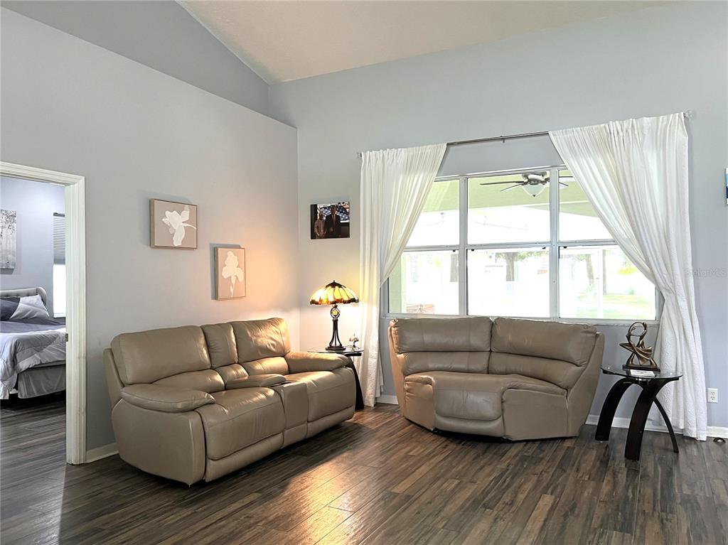 A living room features two tan leather sofas, a stained-glass lamp, and wood-look flooring — 36320 PINEY RIDGE BOULEVARD, FRUITLAND PARK, FL