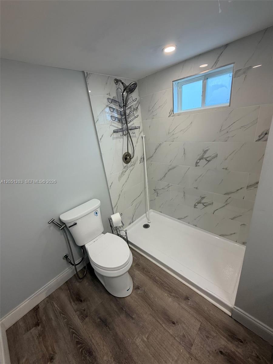 A bathroom features a walk-in shower with marble-look tile, a toilet, and wood-look flooring — 3707 SE 27th St, Okeechobee FL 34974, OKEECHOBEE, FL