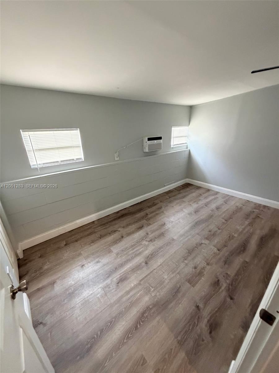 An empty room features light gray walls, wood-look flooring, two windows, and a wall-mounted air conditioner — 3707 SE 27th St, Okeechobee FL 34974, OKEECHOBEE, FL