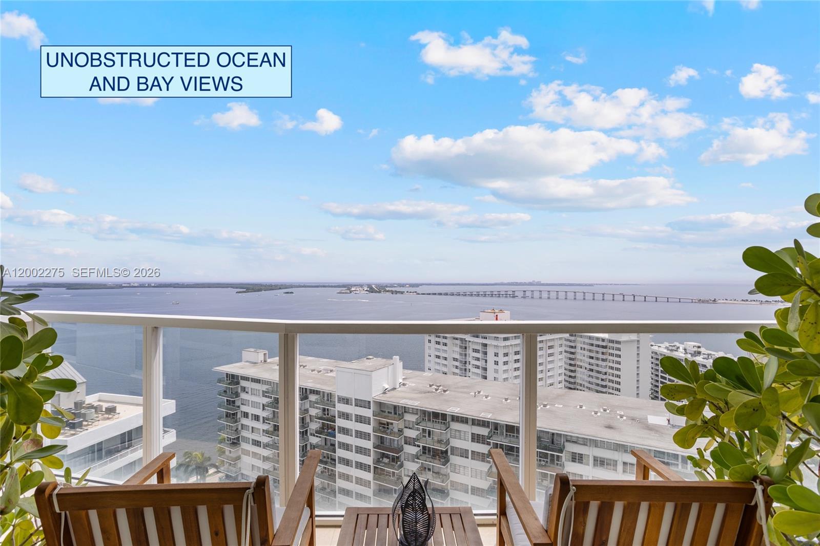 A balcony with two wooden chairs overlooks a bay, a bridge, and high-rise buildings — 218 SE 14th St # 2105, Miami FL 33131, MIAMI, FL
