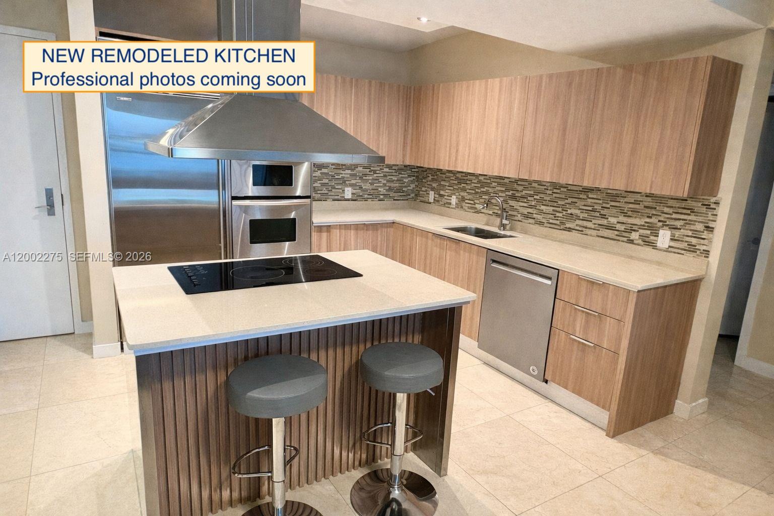 A modern kitchen features light wood cabinets, a stone island with a cooktop, and stainless appliances — 218 SE 14th St # 2105, Miami FL 33131, MIAMI, FL