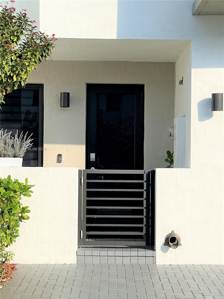 A black metal gate stands before a dark front door on a paved patio — 491 SW 91st Pl, Miami FL 33174, MIAMI, FL