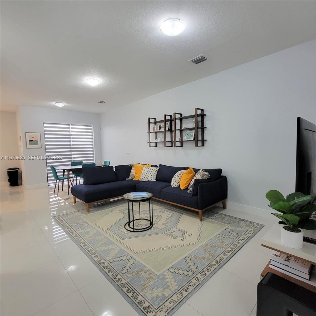 A living room features a dark blue sectional sofa, a patterned rug, and wall shelving — 491 SW 91st Pl, Miami FL 33174, MIAMI, FL