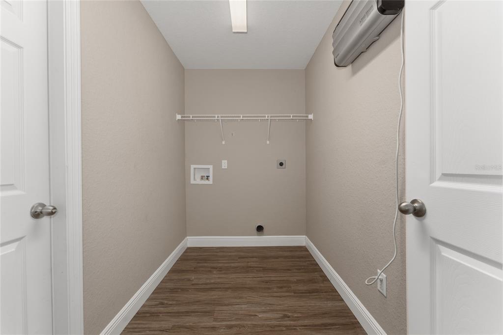 A laundry room with wood-look flooring, a wire shelf, and wall-mounted utility connections — 146 JUNIPER WAY, OCALA, FL