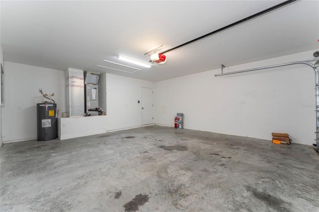 A garage with a concrete floor, a water heater, and an HVAC unit — 146 JUNIPER WAY, OCALA, FL