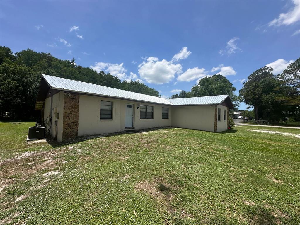 A single-story house with a metal roof and light-colored siding sits on a grassy lot — 17042 NATURE TRAIL, LUTZ, FL