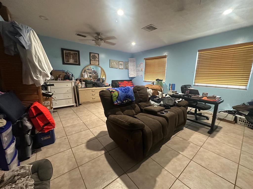 A bedroom with light blue walls, tile flooring, a brown recliner, and a desk — 17042 NATURE TRAIL, LUTZ, FL