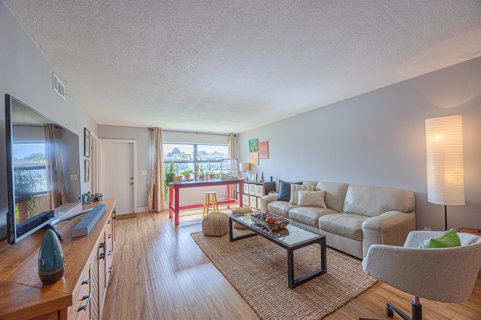 A living room features light wood flooring, a beige sofa, a glass coffee table, and a desk — 3001 SW 21st Terrace # 281a, Delray Beach FL 33445, DELRAY BEACH, FL