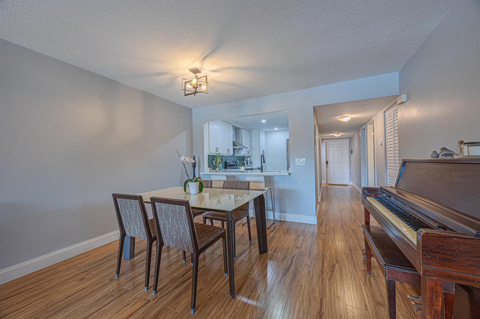 A dining area with a glass table, four chairs, and an upright piano on wood floors — 3001 SW 21st Terrace # 281a, Delray Beach FL 33445, DELRAY BEACH, FL