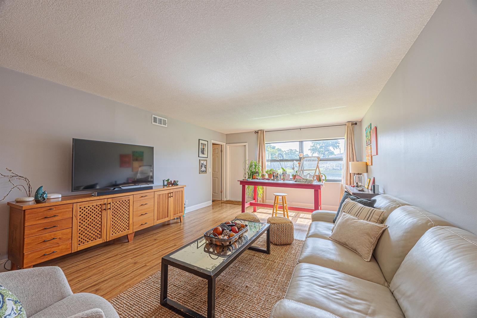A living room features a light-colored sofa, a wooden media console, and a red table — 3001 SW 21st Terrace # 281a, Delray Beach FL 33445, DELRAY BEACH, FL