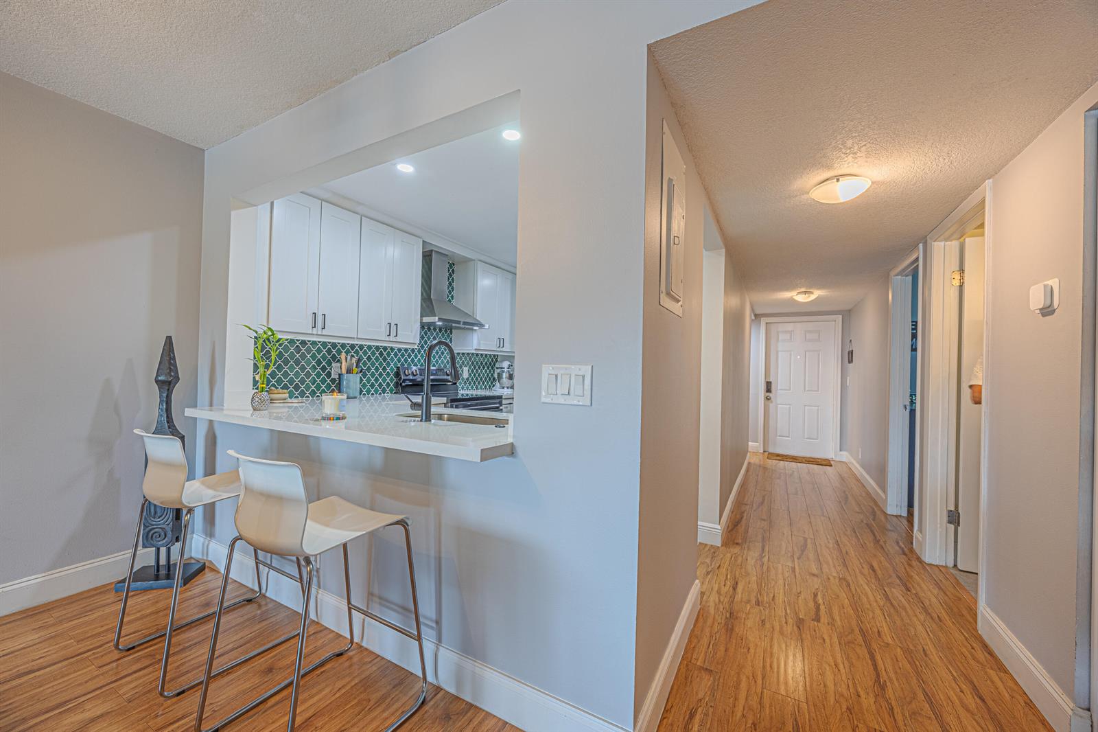 A kitchen with white cabinets and green tile backsplash overlooks a hallway with wood flooring — 3001 SW 21st Terrace # 281a, Delray Beach FL 33445, DELRAY BEACH, FL