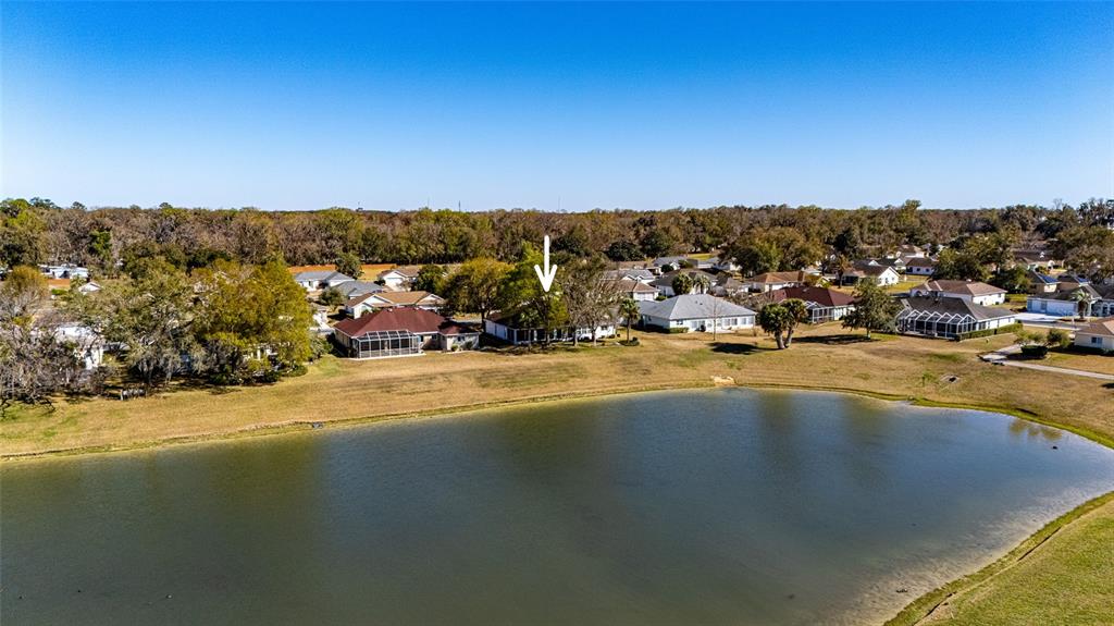 An aerial view shows a residential neighborhood with houses situated along a small lake — 1956 NW 50TH CIRCLE, OCALA, FL