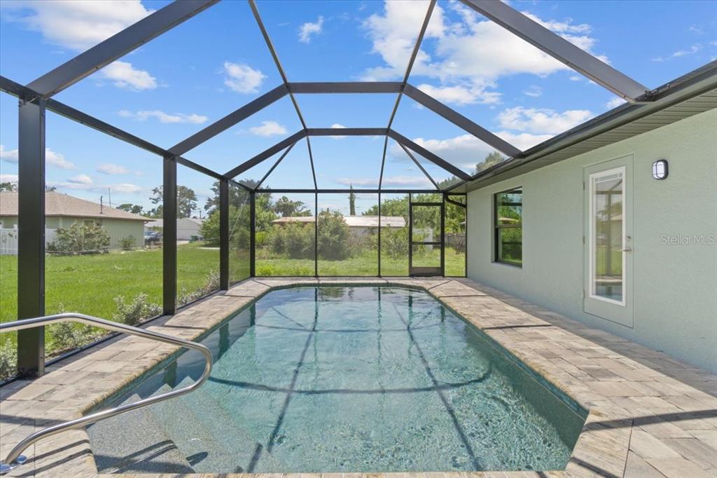 A rectangular swimming pool is enclosed by a black metal screen cage on a patio — 9171 PROSPECT AVENUE, ENGLEWOOD, FL