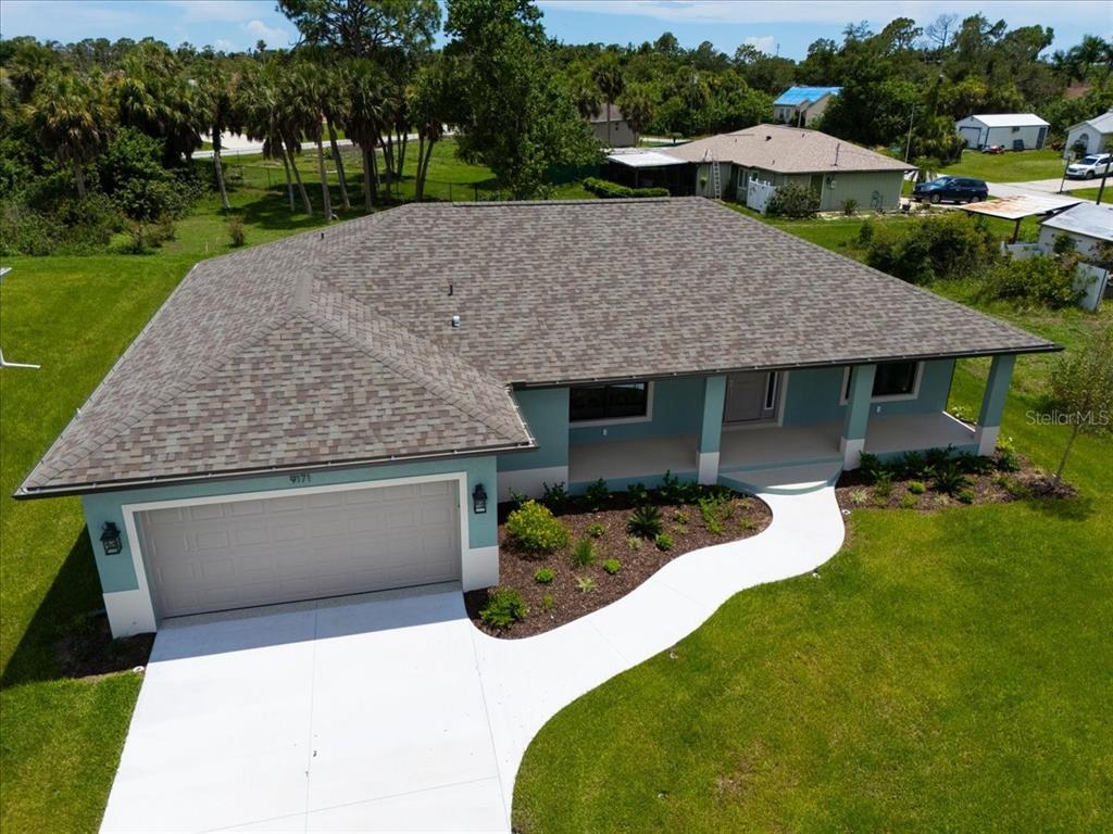 An aerial view of a single-story house with a blue exterior, shingled roof, and garage — 9171 PROSPECT AVENUE, ENGLEWOOD, FL