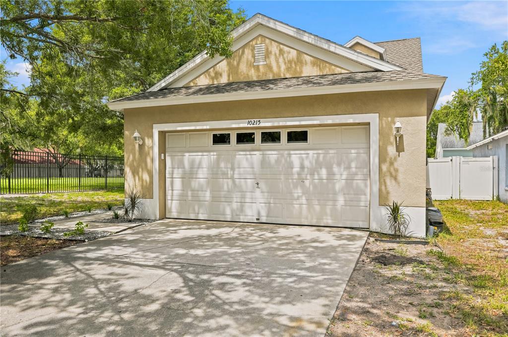 A tan detached garage with a white door, concrete driveway, and a gabled roof — 10215 LAKESIDE VISTA DRIVE, RIVERVIEW, FL