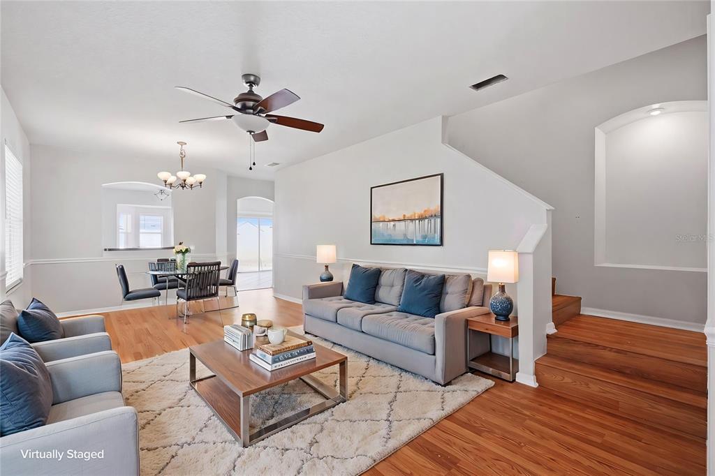 An empty room with wood-look flooring, a ceiling fan, and stairs leading to an upper level — 10215 LAKESIDE VISTA DRIVE, RIVERVIEW, FL