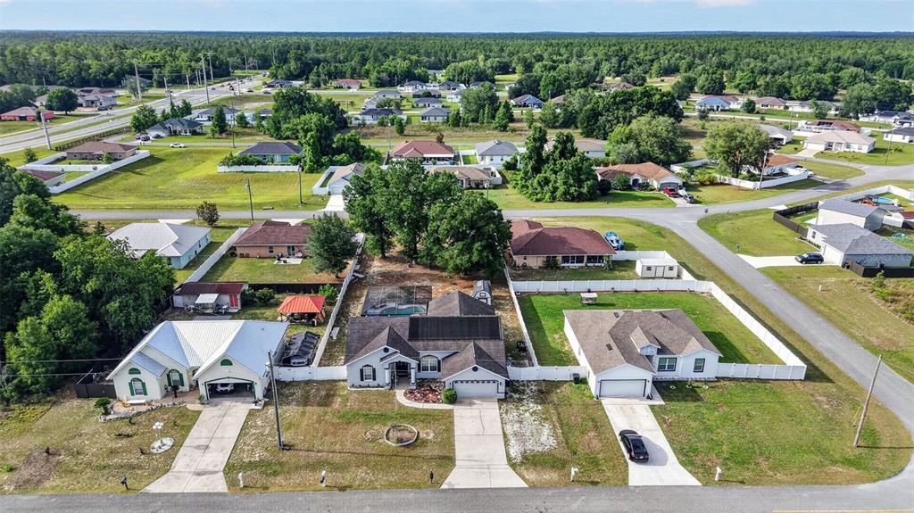 An aerial view shows three suburban houses with fenced backyards and driveways in a neighborhood — 4783 SW 131ST PLACE, OCALA, FL