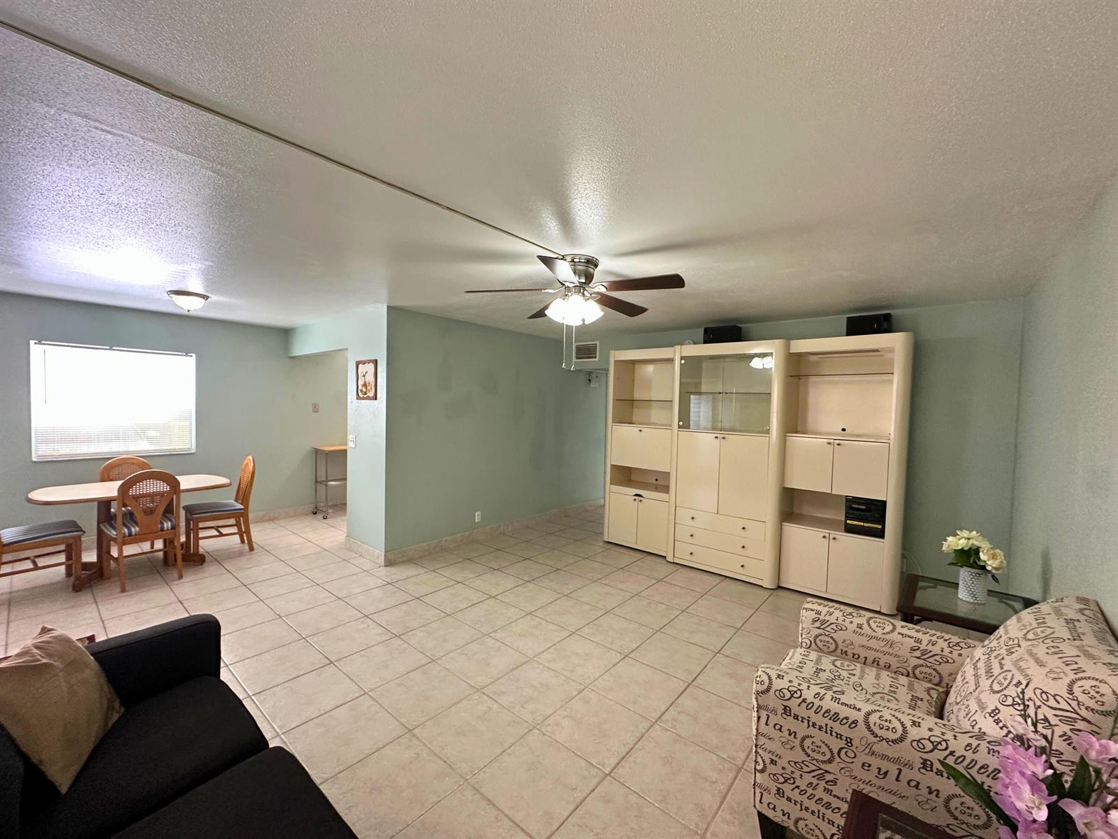 A living and dining area features tile flooring, a ceiling fan, and a large wall unit — 337 Saxony H Way # 337, Delray Beach FL 33446, DELRAY BEACH, FL