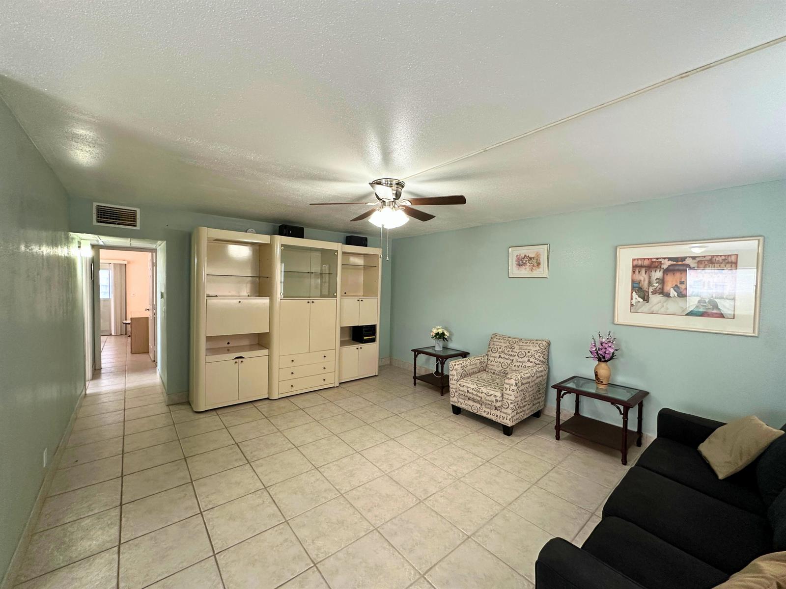 A living room with light blue walls, tile flooring, a ceiling fan, and a large wall unit — 337 Saxony H Way # 337, Delray Beach FL 33446, DELRAY BEACH, FL