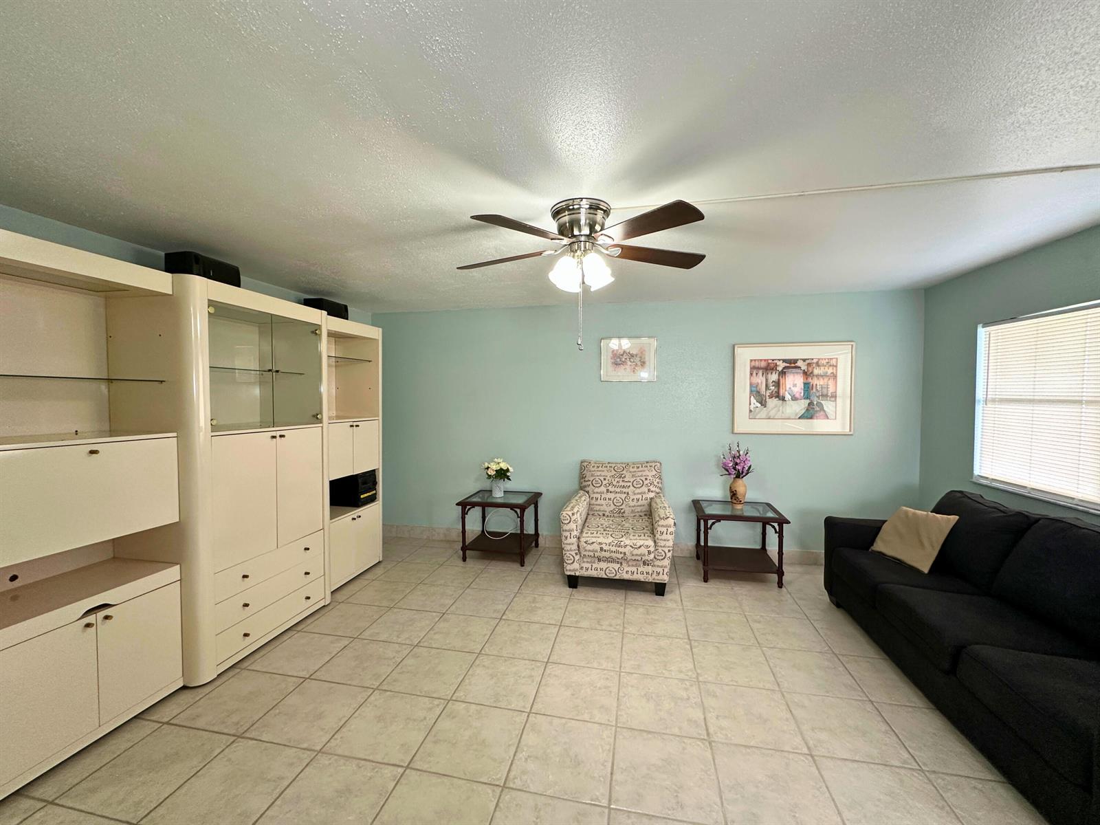 A living room features light blue walls, tile flooring, a ceiling fan, and white cabinetry — 337 Saxony H Way # 337, Delray Beach FL 33446, DELRAY BEACH, FL