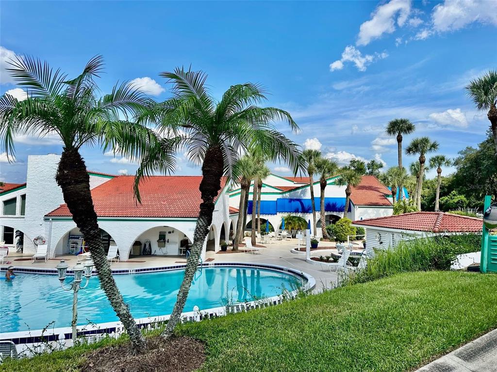 A swimming pool sits in front of a building with a red tile roof — 5435 CASABLANCA CIRCLE UNIT M22, SEBRING, FL
