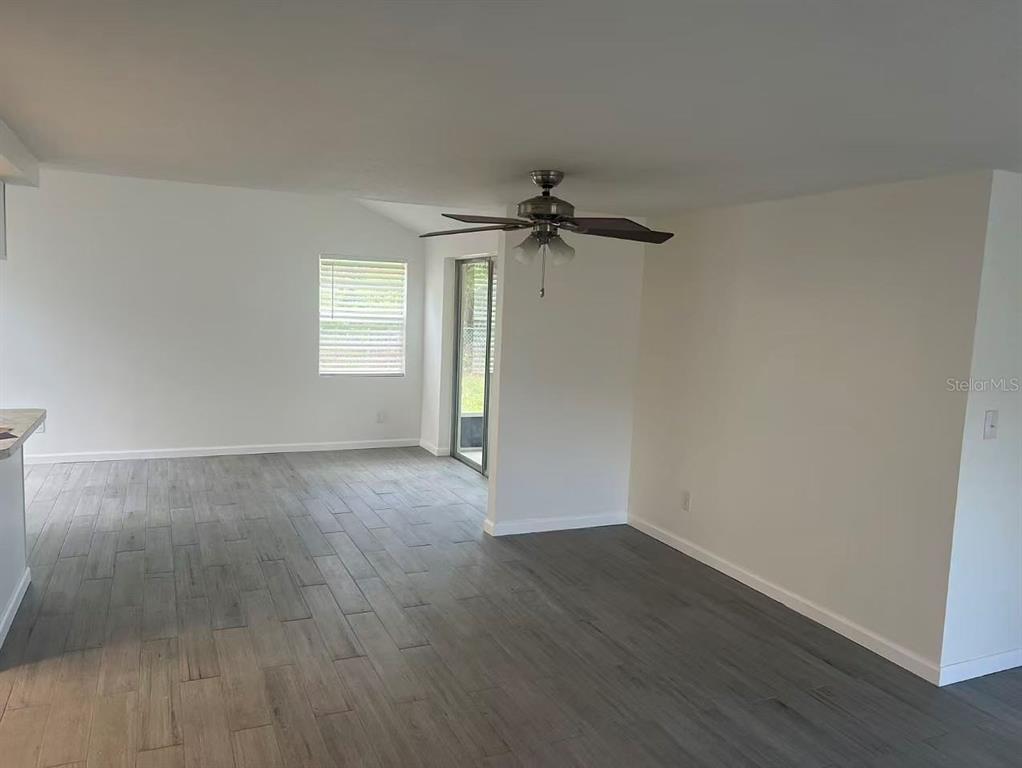 An empty room features gray wood-look tile flooring, white walls, and a ceiling fan — 8516 INWOOD DRIVE, HUDSON, FL