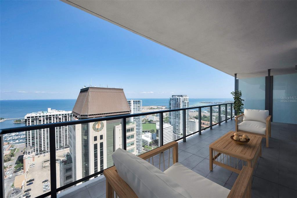 A high-rise balcony features outdoor furniture overlooking a city skyline and the ocean — 275 1ST AVENUE S UNIT 3503, ST PETERSBURG, FL
