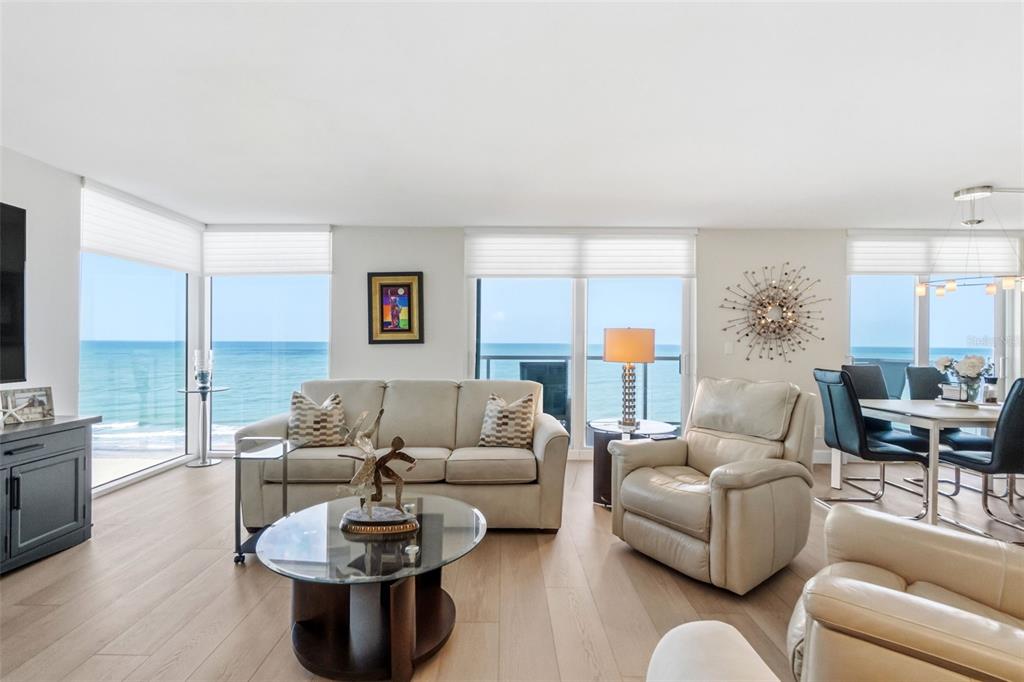 A bright living room features light wood floors, a beige sofa, and floor-to-ceiling ocean views — 2425 GULF OF MEXICO DRIVE UNIT 7C, LONGBOAT KEY, FL
