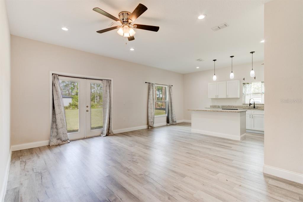 An open-concept living room and kitchen featuring light wood-look flooring and a ceiling fan — 1680 9TH AVENUE, DELAND, FL