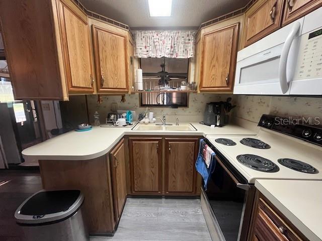 A kitchen features wood cabinets, white countertops, a double sink, and a white electric range — 70 FAIRVIEW DRIVE S, HAINES CITY, FL