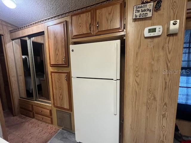 A white refrigerator stands next to wood-paneled cabinets and a closet with sliding mirror doors — 70 FAIRVIEW DRIVE S, HAINES CITY, FL