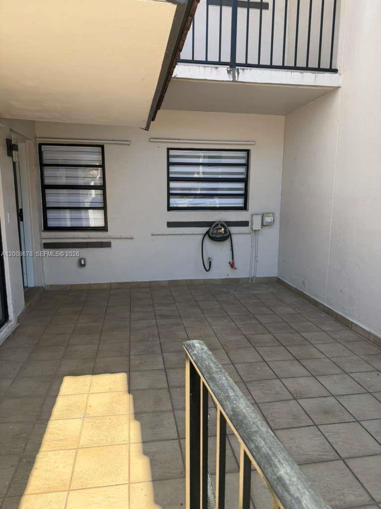 A tiled outdoor patio features two windows with horizontal blinds and a wall-mounted hose — 13470 SW 62nd St # 105N, Miami FL 33183, MIAMI, FL
