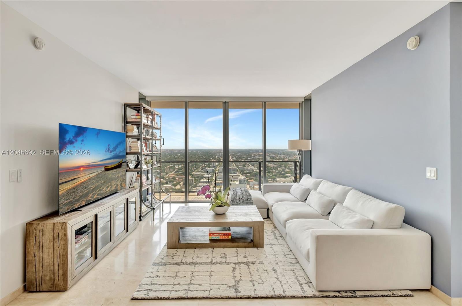 A living room features a white sectional sofa, wooden coffee table, and floor-to-ceiling windows — 88 SW 7th St # 3604, Miami FL 33130, MIAMI, FL