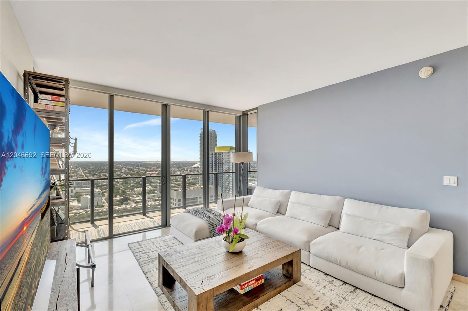 A living room features a white sectional sofa, wooden coffee table, and floor-to-ceiling windows — 88 SW 7th St # 3604, Miami FL 33130, MIAMI, FL