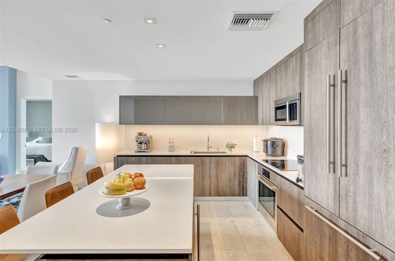 A modern kitchen features wood-grain cabinetry, a white island, and stainless steel appliances — 88 SW 7th St # 3604, Miami FL 33130, MIAMI, FL