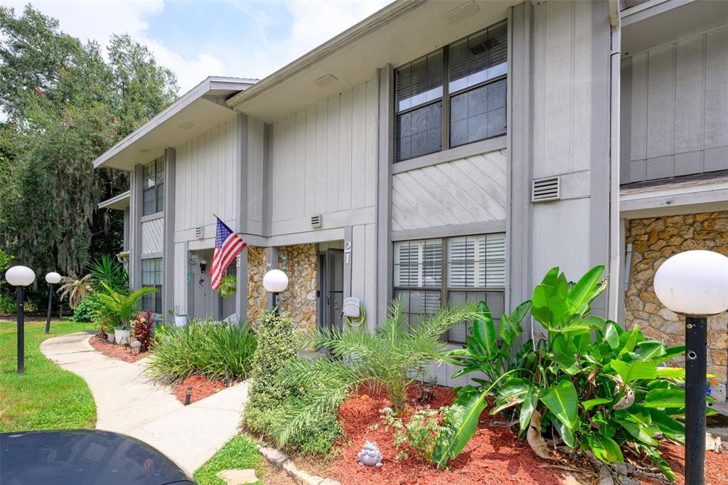 The exterior of a two-story apartment building features light siding, stone accents, and a walkway — 21 OAKWOOD PARK, ORMOND BEACH, FL