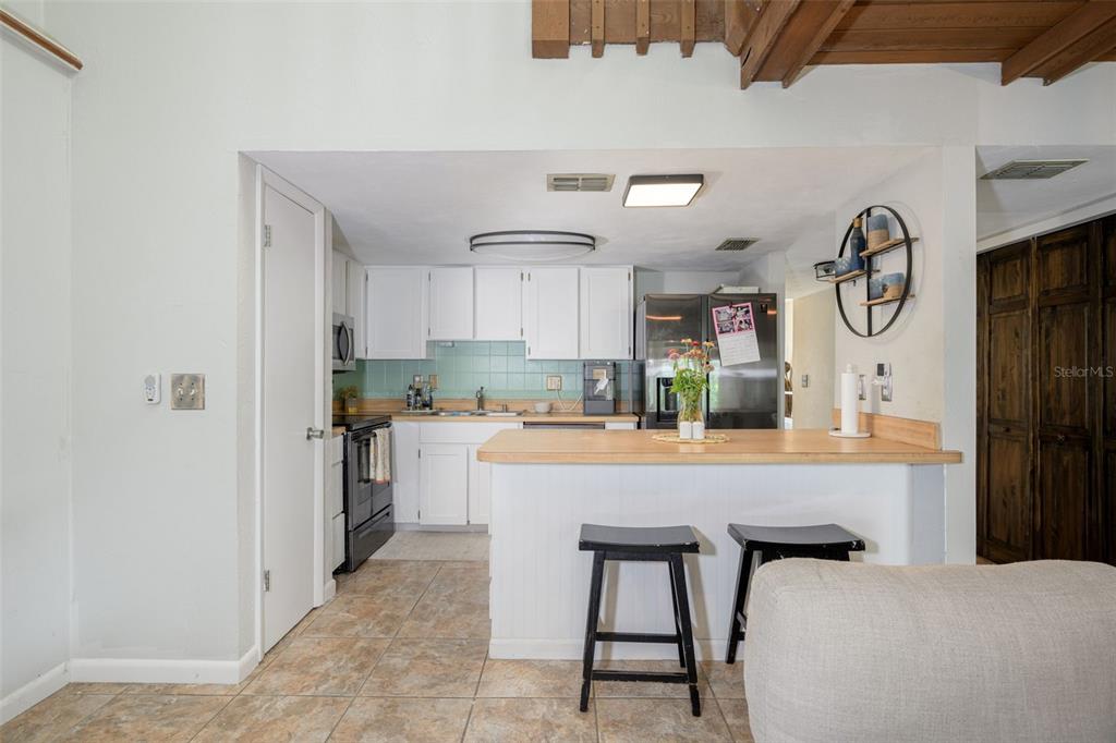 A kitchen with white cabinets, a light wood breakfast bar, and tile flooring — 21 OAKWOOD PARK, ORMOND BEACH, FL