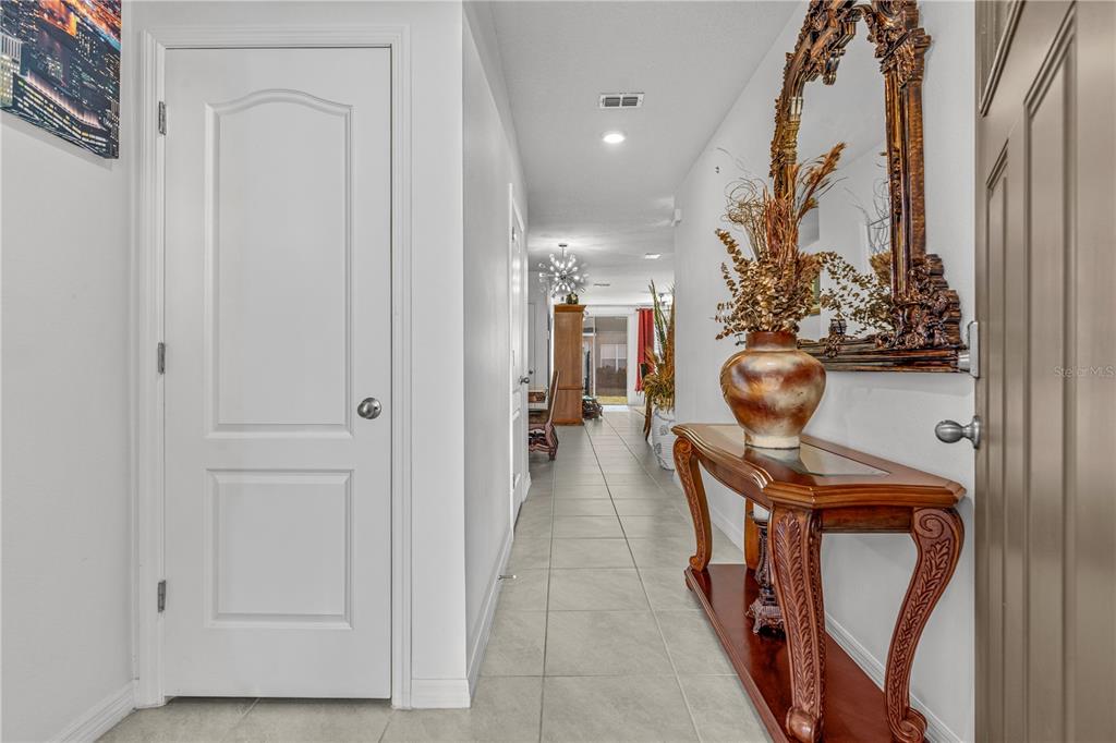 A tiled entryway features a white door, a console table with a mirror, and a hallway — 57 BELLA LAGO CIRCLE, PORT ORANGE, FL