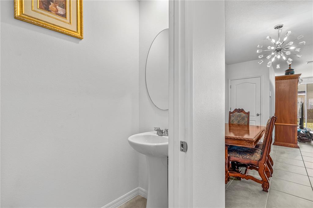 A small powder room with a pedestal sink and mirror opens into a dining area — 57 BELLA LAGO CIRCLE, PORT ORANGE, FL